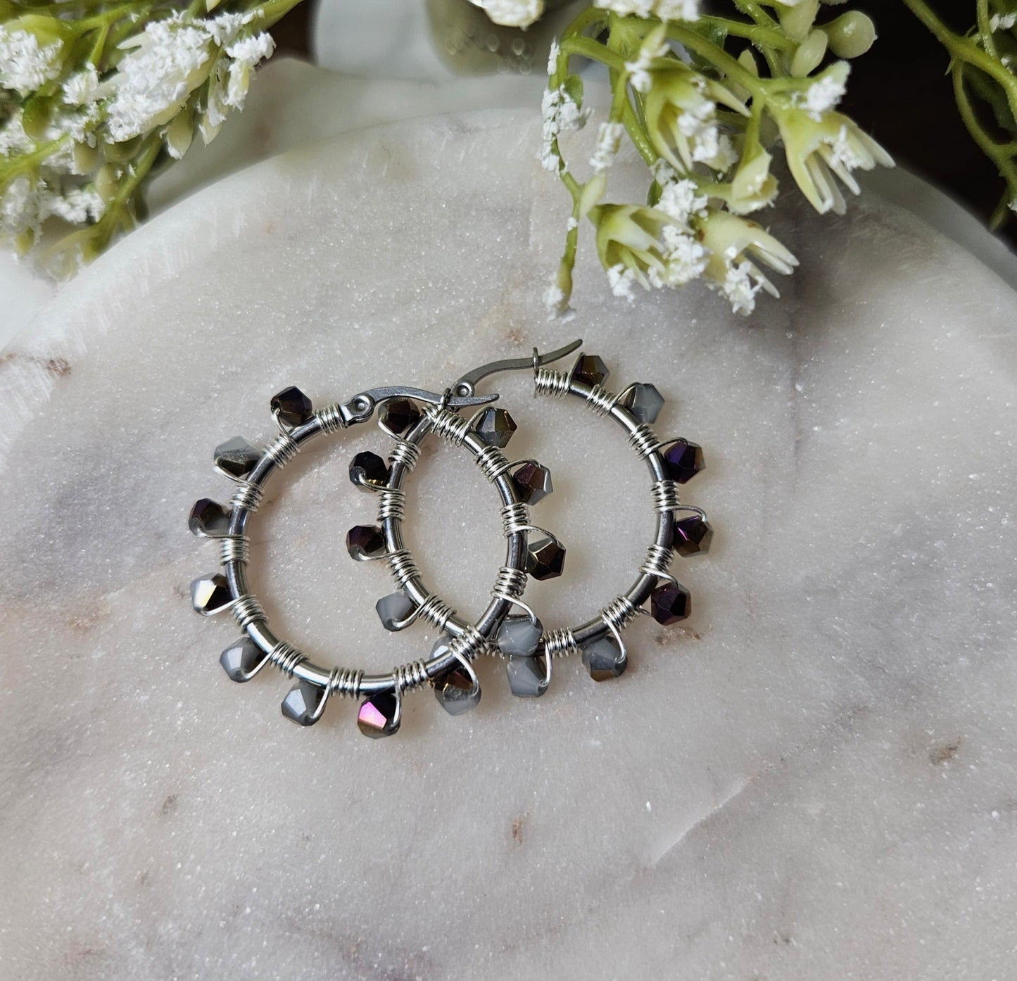 argollas Noche Estelar: aros plateados con cuentas de brillo oscuro y elegante