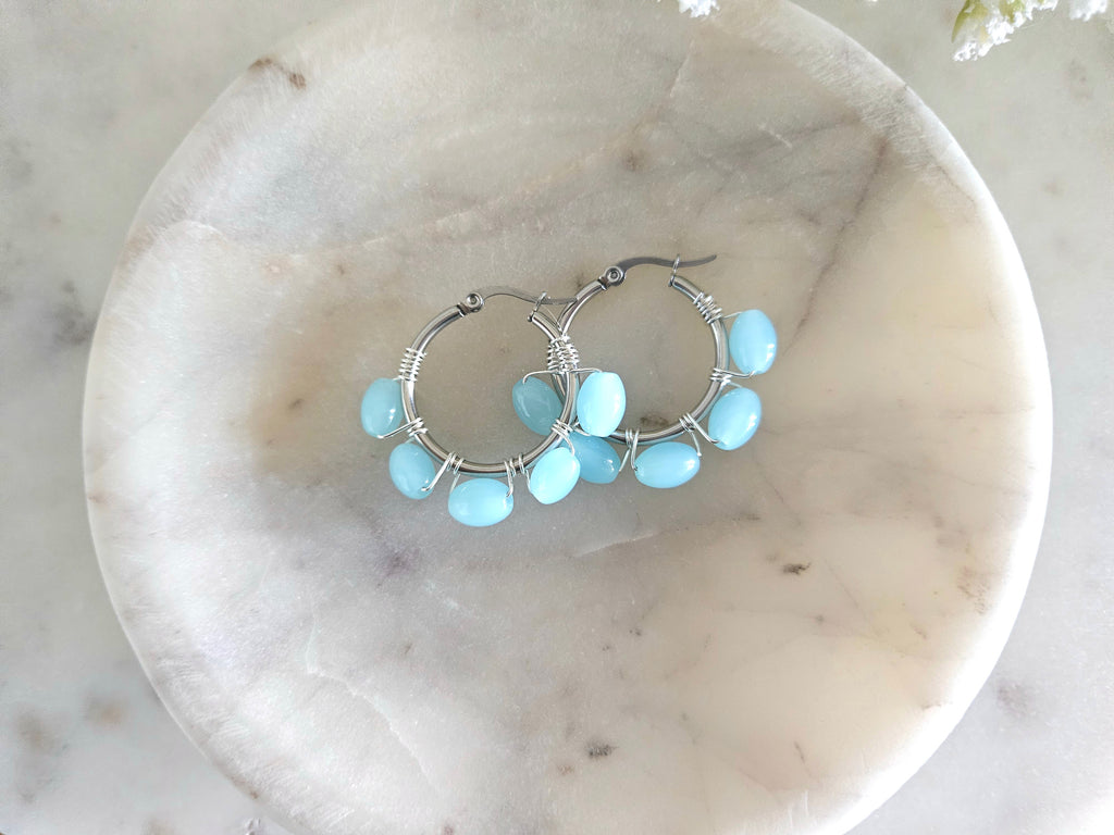 Aros plateados de acero inoxidable con delicados cristales azul cemento envueltos con alambre AAA plateado.